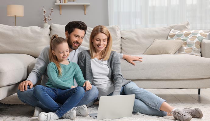 Family on living room with a laptop enjoying clean air after smoke odor removal service