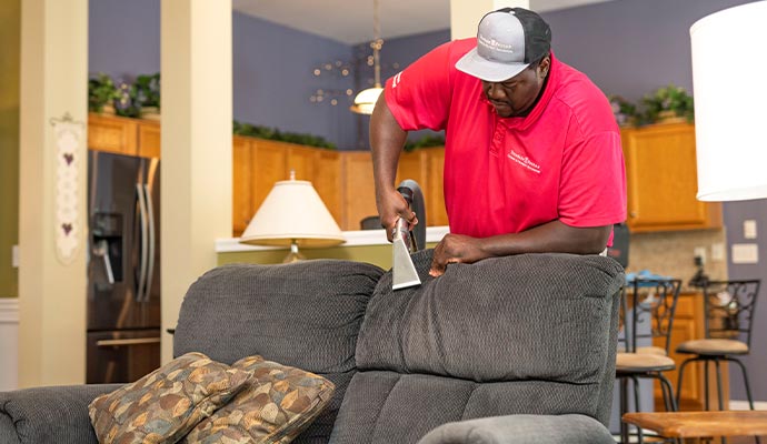 Person cleaning upholstery using equipment