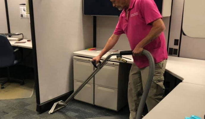 Professional worker cleaning carpet with portable extraction
