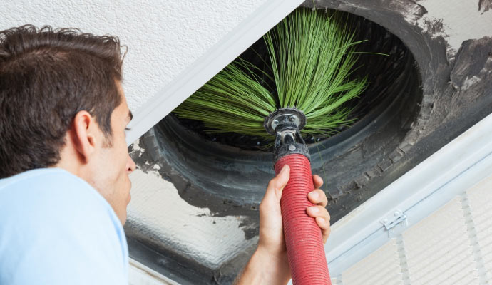 A technician cleaning an air duct in a home.