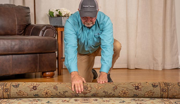 Teasdale employee rolling up a rug for pickup service