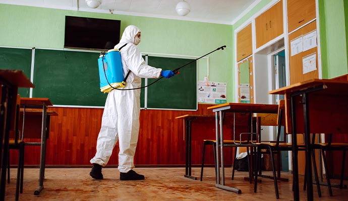 Professional worker sanitizing a class room